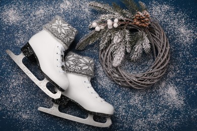 Photo of Pair of ice skates with Christmas decor on blue wooden background, flat lay