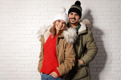 Photo of Young couple wearing warm clothes against brick wall. Ready for winter vacation