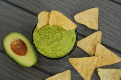 Photo of Delicious guacamole, avocado and nachos on wooden table, flat lay