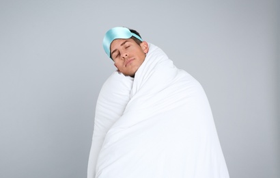 Photo of Man wrapped in blanket sleeping on grey background. Space for text