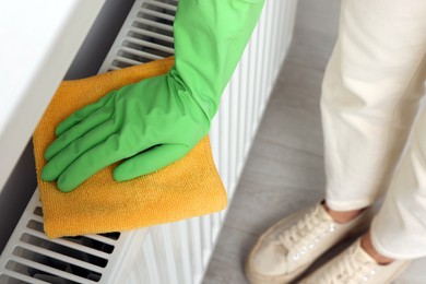 Photo of Woman cleaning white radiator with rag indoors, above view