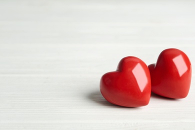 Photo of Decorative hearts on white wooden table, space for text. Valentine's Day