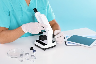 Photo of Male doctor using microscope at table, closeup. Medical object