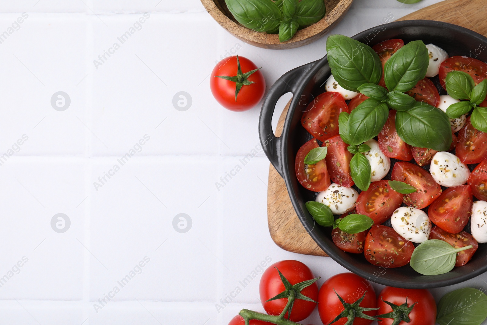 Photo of Tasty salad Caprese with mozarella balls, tomatoes and basil on white tiled table, flat lay. Space for text