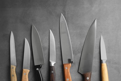 Photo of Many different knives on grey textured table, flat lay
