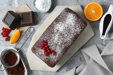 Photo of Tasty chocolate sponge cake and ingredients on light grey table, flat lay
