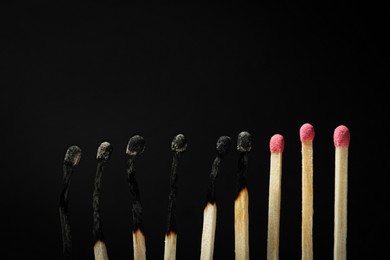 Photo of Burnt and whole matches on black background, closeup. Stop destruction concept