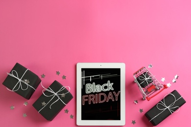 Photo of Tablet with Black Friday announcement and gifts on pink background, flat lay. Space for text