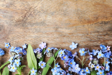 Photo of Beautiful forget-me-not flowers and space for text on wooden background, flat lay