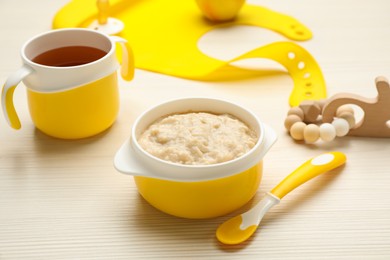 Plastic dishware with healthy baby food on white wooden table