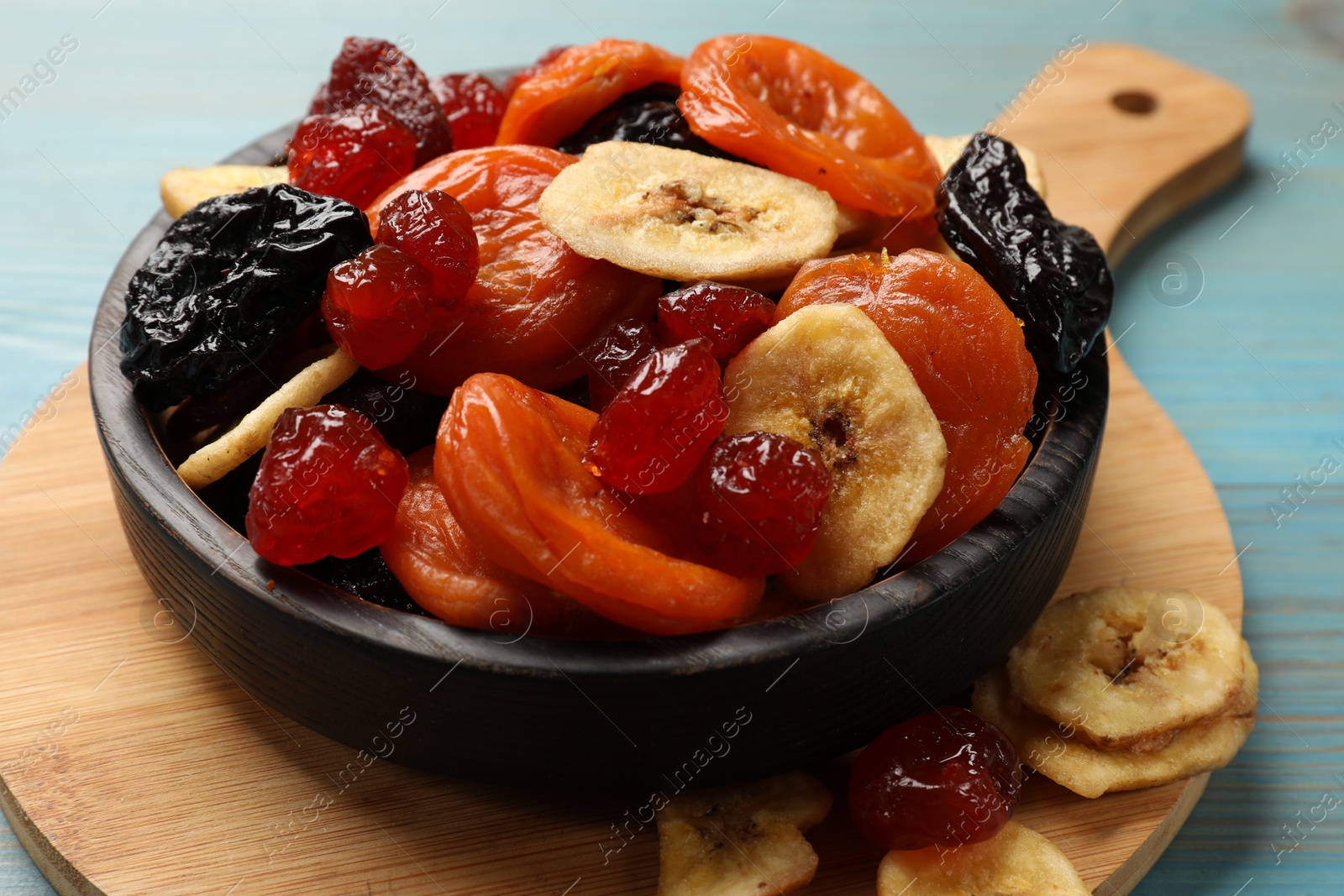 Photo of Mix of delicious dried fruits on light blue wooden table, closeup