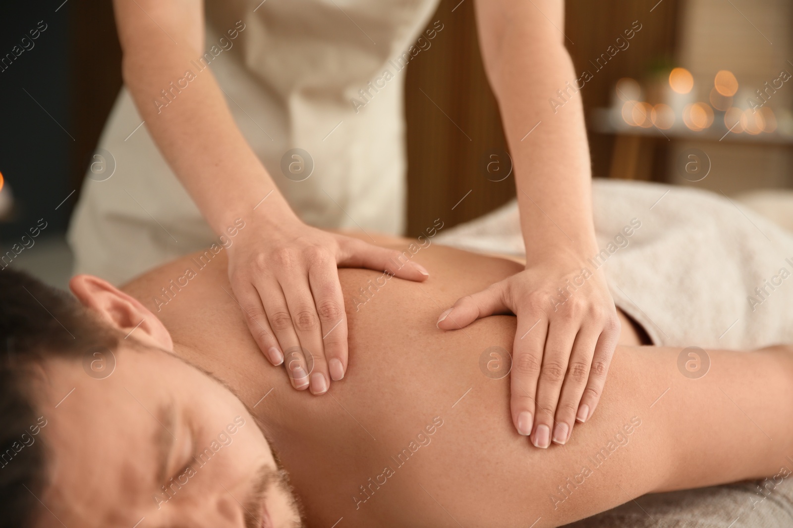 Photo of Handsome man receiving back massage in spa salon, closeup