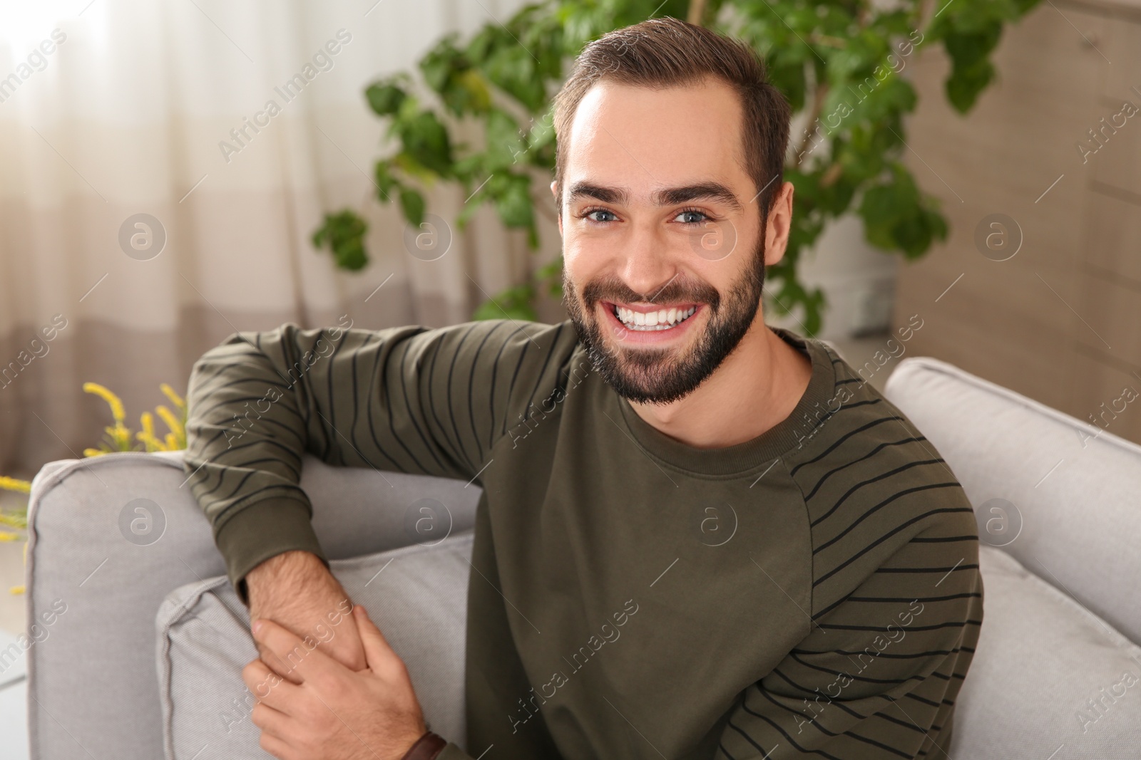 Photo of Portrait of young man laughing at home