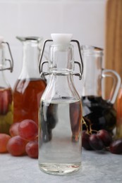 Different types of vinegar and grapes on grey table