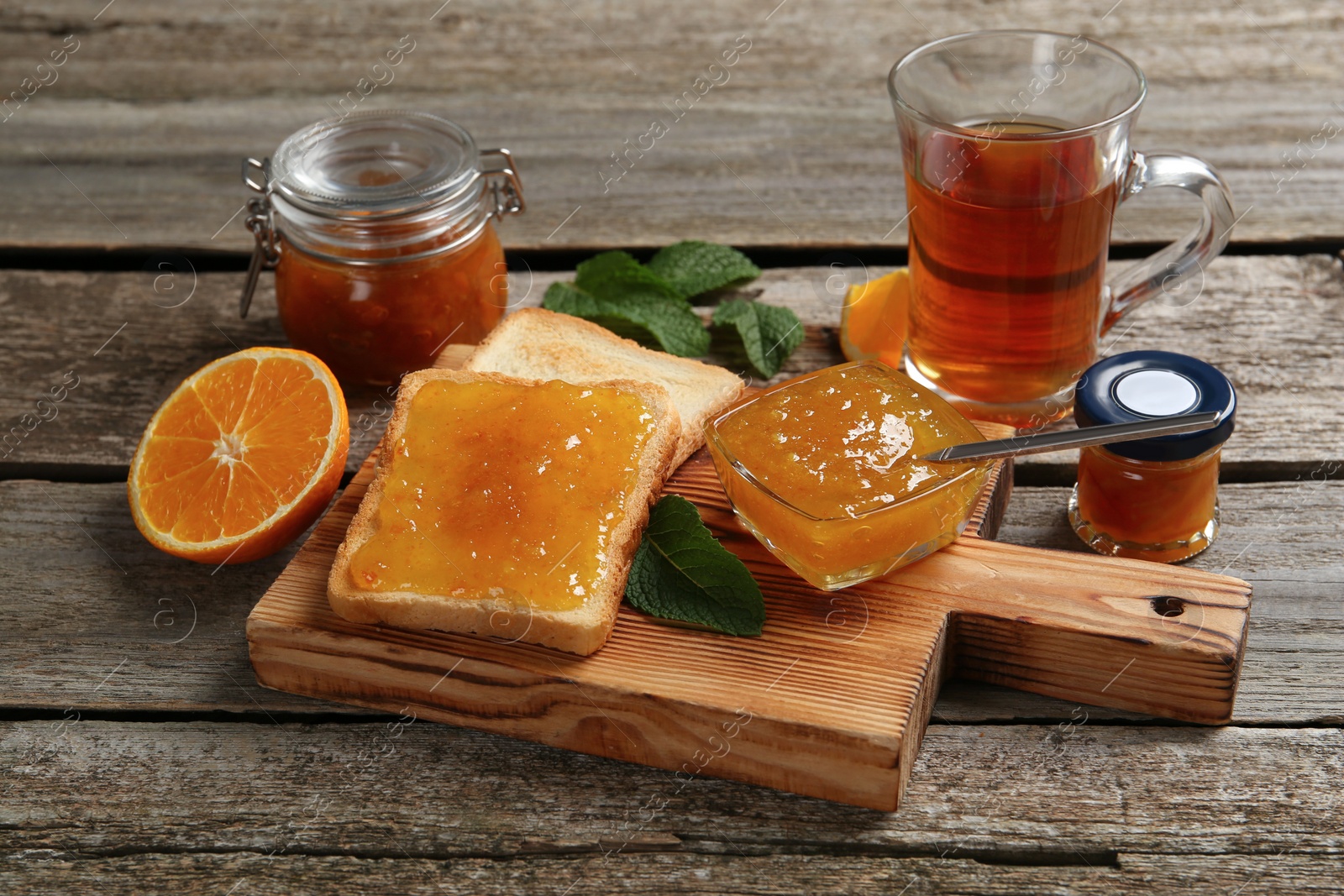 Photo of Delicious toasts served with jam and tea on wooden table