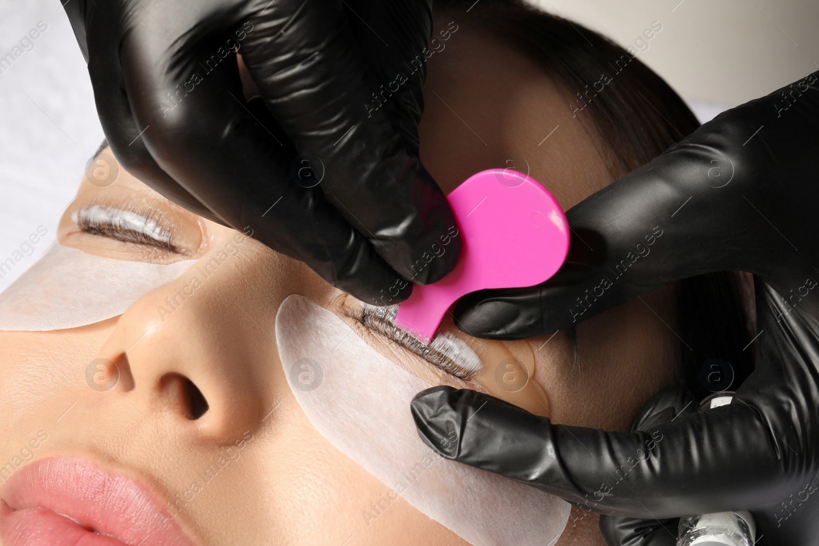 Photo of Young woman undergoing eyelash lamination, closeup. Professional service