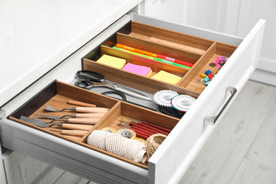 Sewing accessories and stationery in open desk drawer indoors