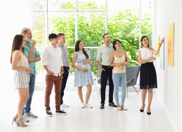 Group of people with guide at exhibition in art gallery