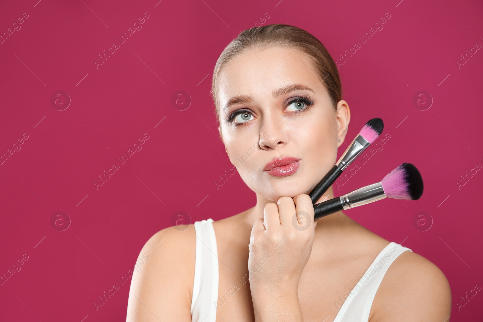 Photo of Beautiful woman with makeup brushes on pink background