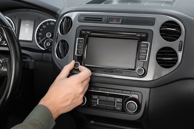 Photo of Listening to radio while driving. Man turning volume button on vehicle audio in car, closeup
