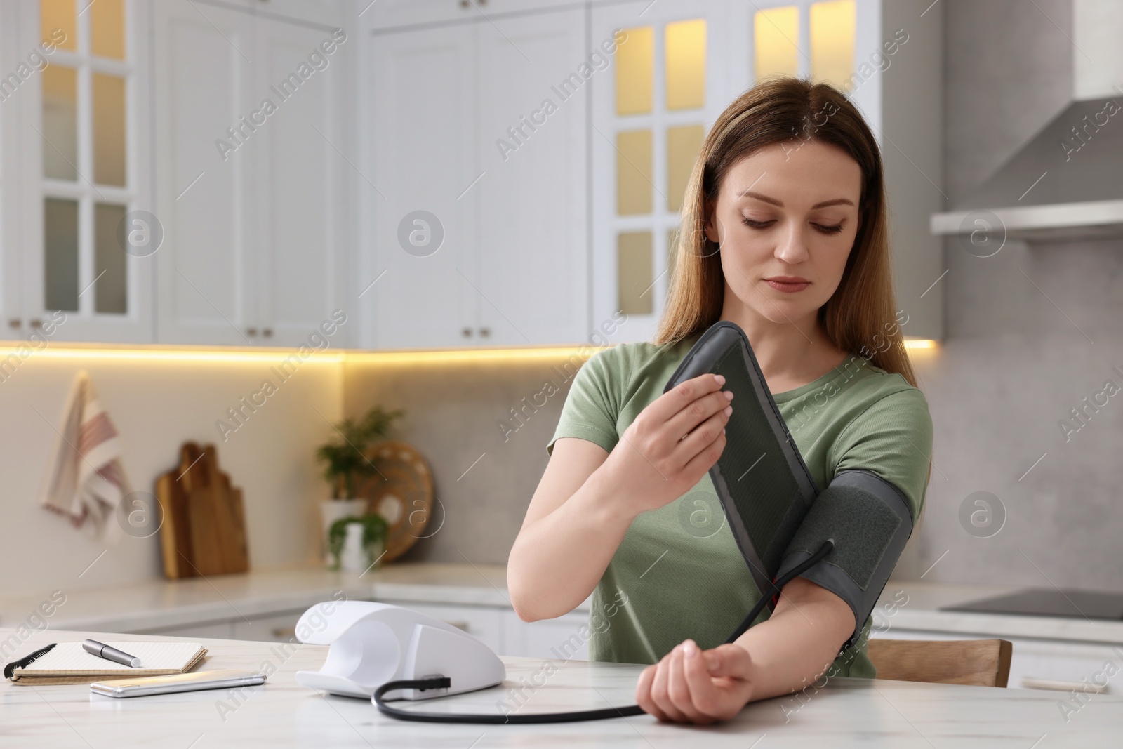 Photo of Woman measuring blood pressure in kitchen, space for text