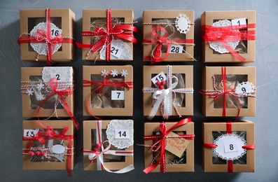 Set of gift boxes with Christmas decor on light grey stone table, flat lay. Advent calendar