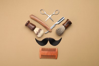 Photo of Artificial moustache and barber tools on beige background, flat lay