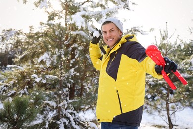 Happy man with snowball outdoors on winter day. Christmas vacation