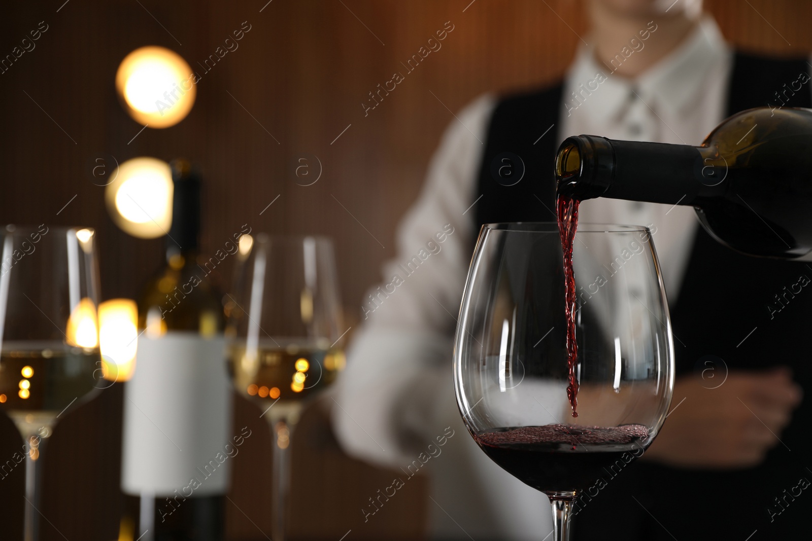 Photo of Waitress pouring wine into glass in restaurant, closeup