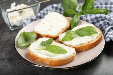 Photo of Delicious sandwiches with cream cheese and basil leaves on grey table, closeup