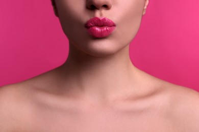 Photo of Closeup view of beautiful woman puckering lips for kiss on pink background