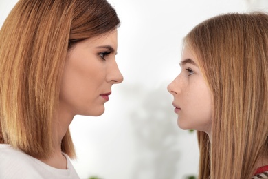 Mother and her teenager daughter looking at each other indoors