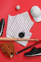 Photo of Flat lay composition with baseball uniform and sports equipment on red background
