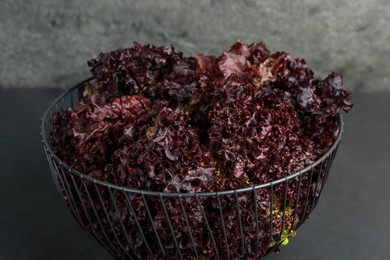 Photo of Metal bowl with red coral lettuce on grey table