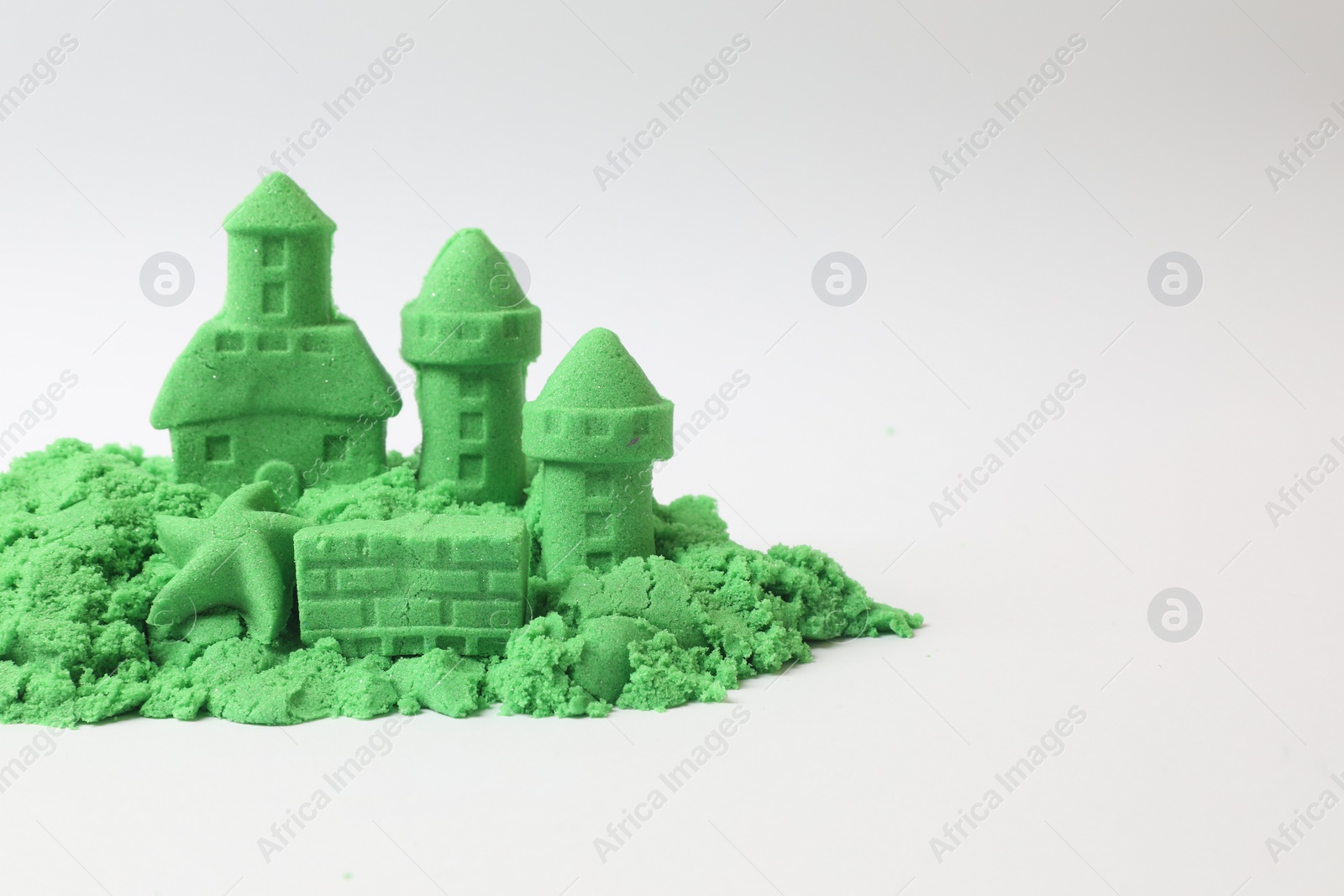 Photo of Castle figures and starfish made of green kinetic sand isolated on white