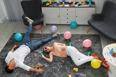 Photo of Drunk friends sleeping on floor in messy room after party