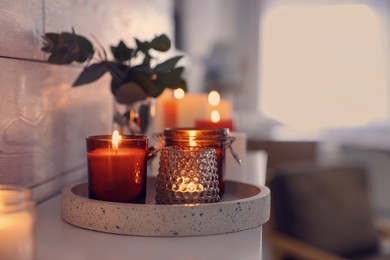 Photo of Burning candles on mantel near white wall indoors, space for text