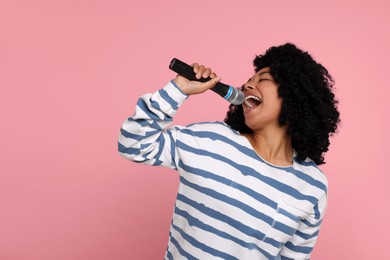 Photo of Beautiful woman with microphone singing on pink background, space for text