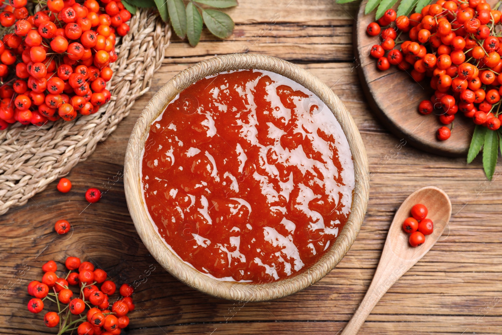 Photo of Flat lay composition with delicious rowan jam and berries on wooden table