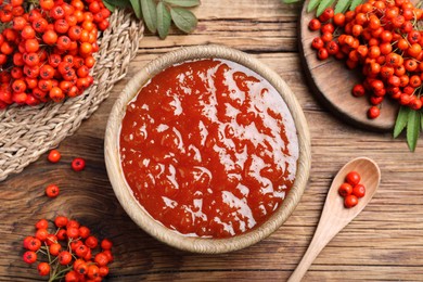 Photo of Flat lay composition with delicious rowan jam and berries on wooden table