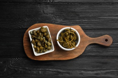 Photo of Tasty capers on black wooden table, top view