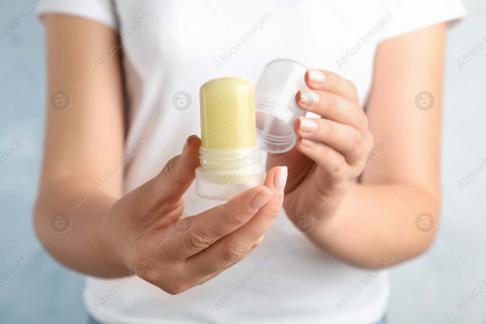 Photo of Young woman holding natural crystal alum stick deodorant, closeup