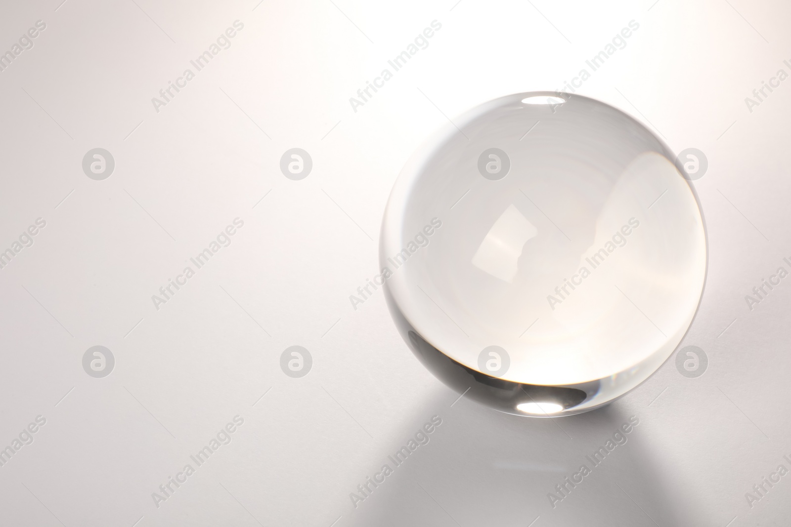 Photo of Transparent glass ball on light grey background. Space for text