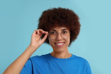 Portrait of happy young woman in eyeglasses on light blue background