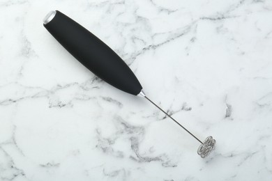 Black milk frother wand on white marble table, top view