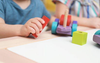 Photo of Little children playing with construction set at table, closeup