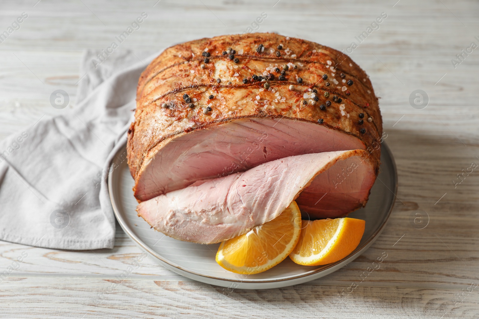 Photo of Delicious baked ham and orange slices on white wooden table, closeup