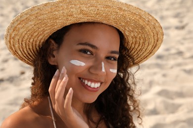 Photo of Beautiful African American woman with sun protection cream on face at sandy beach