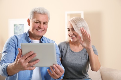 Mature couple using video chat on tablet at home