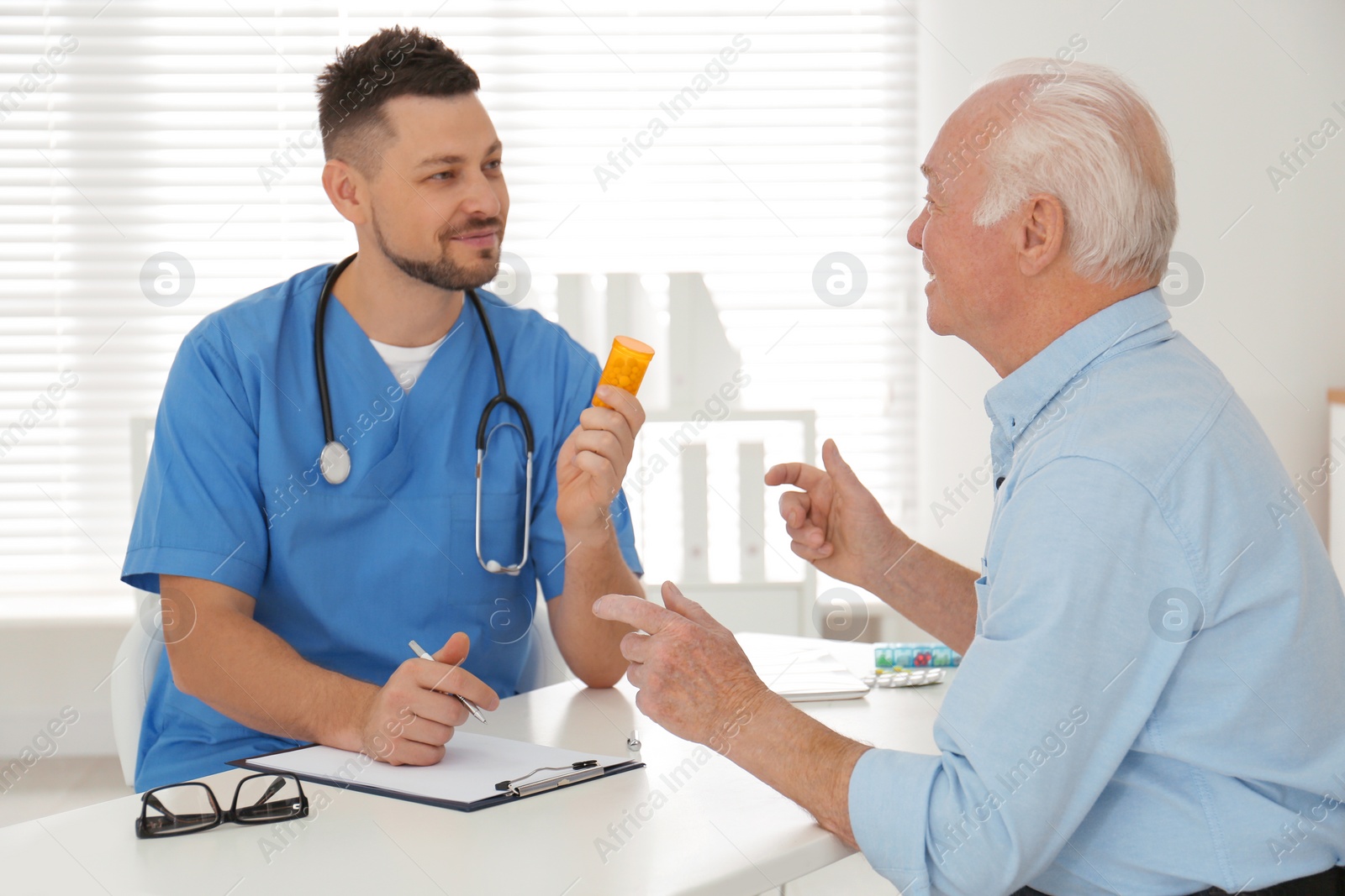 Photo of Doctor giving pills to senior patient in office